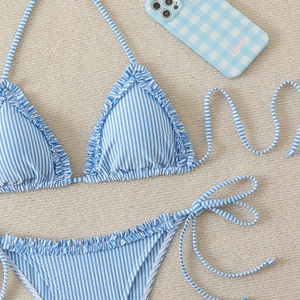 Flat lay of blue striped bikini set with ruffled edges and side-tie bottom on a woven rug