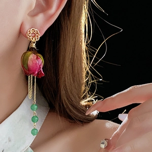 Modell mit langen Perlenohrringen mit rosa Rosenknospen und eleganten goldenen Quasten