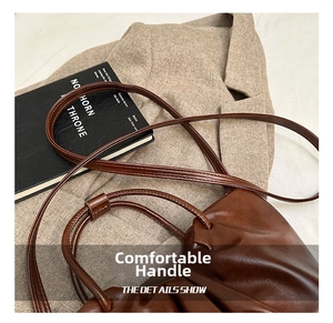 Detailed view of dark brown pleated leather bag with fine texture and slim shoulder strap