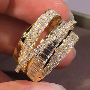 Detail of multi-layer crisscross gold ring with zircon stones held by hand