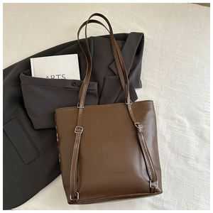Top view of deep brown large-capacity PU leather tote bag on textured white bedding