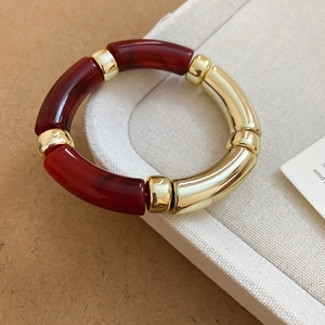 Détails des perles en acrylique marbre rouge foncé et accents dorés sur le bracelet chic