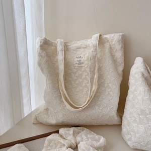 Detail of beige lace embroidery tote bag with animal pattern label and matching accessories