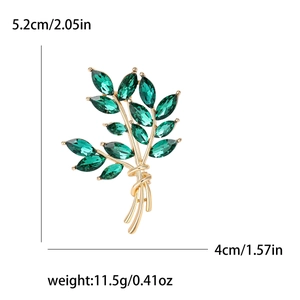 Wheat ear brooch in gold metal with emerald green crystals on white background