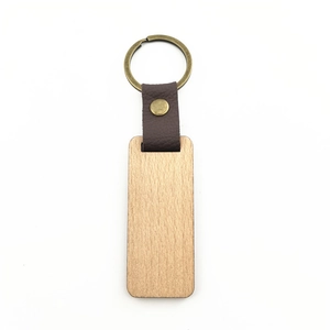 Detail of walnut wood keychain with dark brown leather strap and bronze metal ring