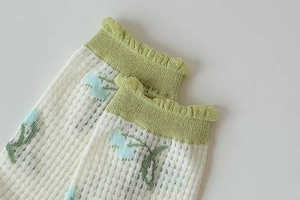 Detailed close-up of breathable mesh socks with green ruffled cuffs and blue floral patterns