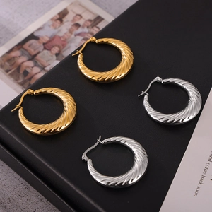 Gold and silver twisted C-shaped hoop earrings in titanium steel displayed on black texture