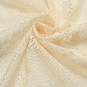 Close-up of cream lace tablecloth fabric showing intricate mesh patterns and soft texture