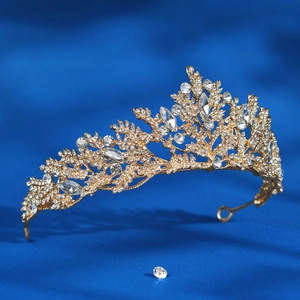 Detailed view of luxury bridal crown with golden branches and clear crystals on blue fabric