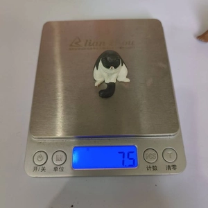 Detail shot of sleeping cat figurine on a digital scale showing weight of 7.5g