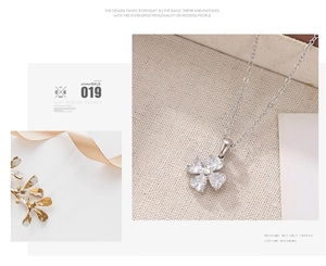 Detailed macro view of silver clover pendant with heart-shaped white cubic zirconia stones