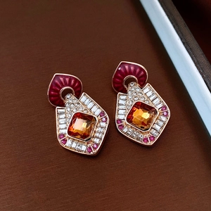Detailed close-up of vintage gold earrings with orange gems and red accents