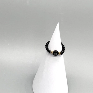 Close-up of beaded evil eye ring with black faceted beads on a display cone