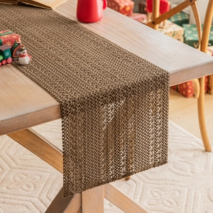 Brown crochet Christmas table runner with festive holiday decor on wooden dining table