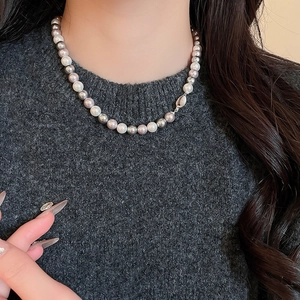 Detailed close-up of French-style tri-color pearl necklace on a textured knit sweater