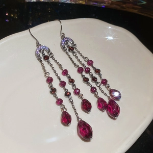 Détail de boucles d'oreilles à franges avec cristaux rose foncé et chaînes en métal noir