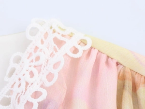 Dettaglio dello scollo in chiffon rosa con pizzo bianco e finiture con bordino giallo