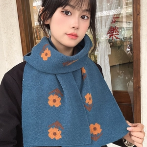 Close-up of knit scarf showing vibrant orange flower patterns on a deep blue background
