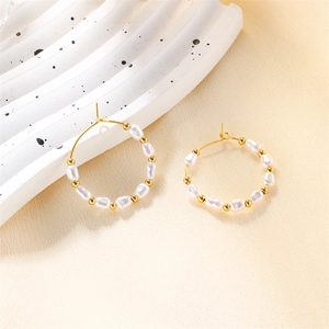 Elegant gold titanium steel hoop earrings with freshwater pearls on beige fabric