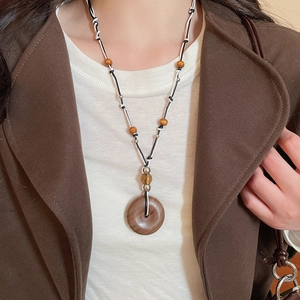Detail of vintage wooden circle pendant necklace with brown resin beads and woven cord