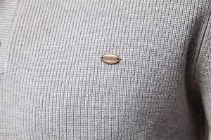 Detailed macro view of grey knit fabric texture with oval metallic brand logo plate