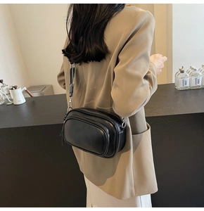 Detail of black multi-zipper leather crossbody bag with wide shoulder strap on model