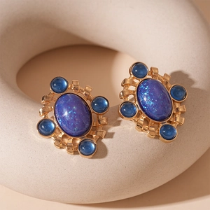 Close-up of vintage oval enamel earrings with blue gemstones and gold-toned metal finish