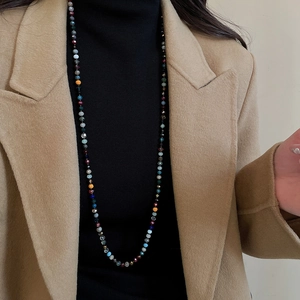 Detailed view of colorful multi-faceted crystal beaded necklace on black turtleneck sweater