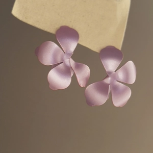 Dettaglio ravvicinato di orecchini a fiore viola opaco con eleganti perni in argento