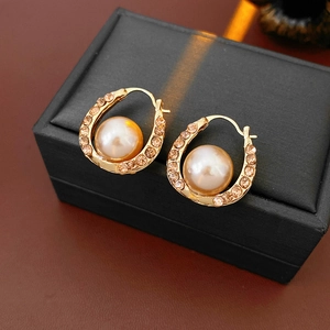 Detailed shot of gold horseshoe earrings with pearl and diamonds on a jewelry box
