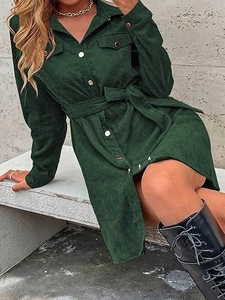 Detail of dark green corduroy shirt dress with metallic buttons and textured fabric finish