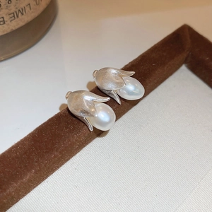 Dettaglio ravvicinato di orecchini a forma di tulipano in argento con perle su velluto