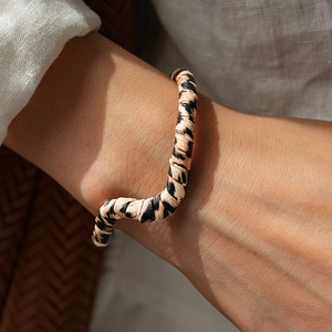Close-up of animal leopard print leather wrap bangle on a model's wrist with warm natural lighting