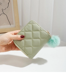Détail du mini portefeuille matelassé vert sauge avec fermeture éclair et pompon