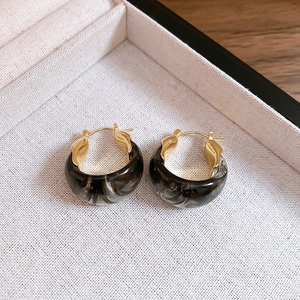 Detail view of U-shaped marble texture resin earrings with polished gold metal clasps