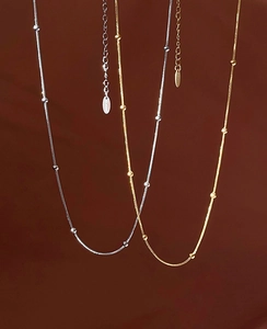 Detailed view of gold and silver snake bone chain necklaces with minimalist metal beads
