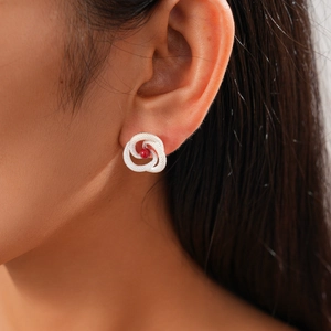 Detail of silver twisted swirl earring with a red pearl on model ear
