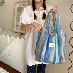 Détail d'un grand sac fourre-tout rayé en laine avec étiquette sur chemise blanche