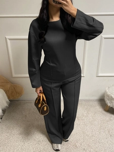 Women's dark grey long-sleeve top and wide-leg trouser set shown in a lifestyle setting