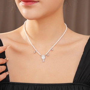 Detail of beaded pearl necklace with silver diamond-encrusted teardrop pendant on model