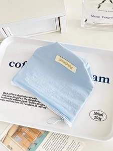 Minimalist sky blue storage bag with white zipper and fabric label for cosmetics
