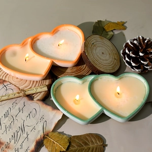 Dual heart scented candles with orange and green borders on rustic wood and parchment