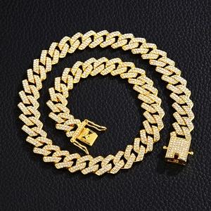 Macro detail of gold Cuban link necklace with sparkling zircons on black leather
