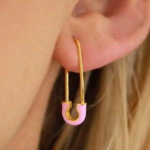 Fashionable golden safety pin earrings with pink enamel detail worn by a model