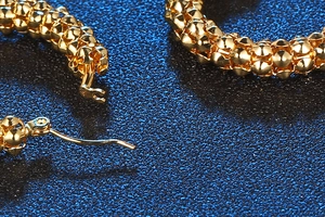 Macro shot of gold-tone textured hoop earrings with bead surface and secure clasp