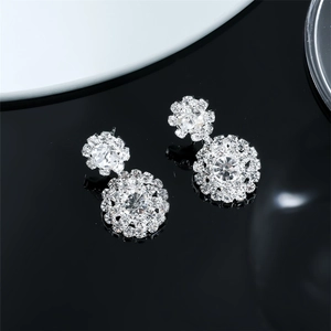 Macro detail of silver snowflake earrings with sparkling rhinestones on black background