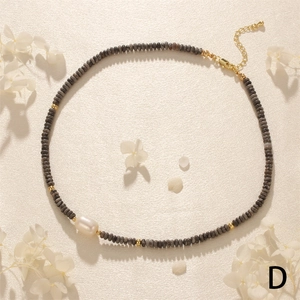 Detail view of tiger eye beads and baroque pearl necklace with golden metal extension chain