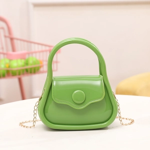 Mini green PVC jelly handbag with gold chain strap and integrated handle on a white table