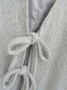 Makro-Detail von flauschigem hellgrauem Wollstoff und Bindeband mit glattem Innenfutter