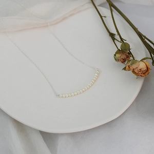 Close-up of small freshwater pearl necklace arranged on a white ceramic plate